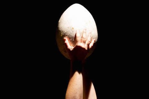 Actress holding up egg prop during Nest music theater at Laus Polyphoniae (2022)